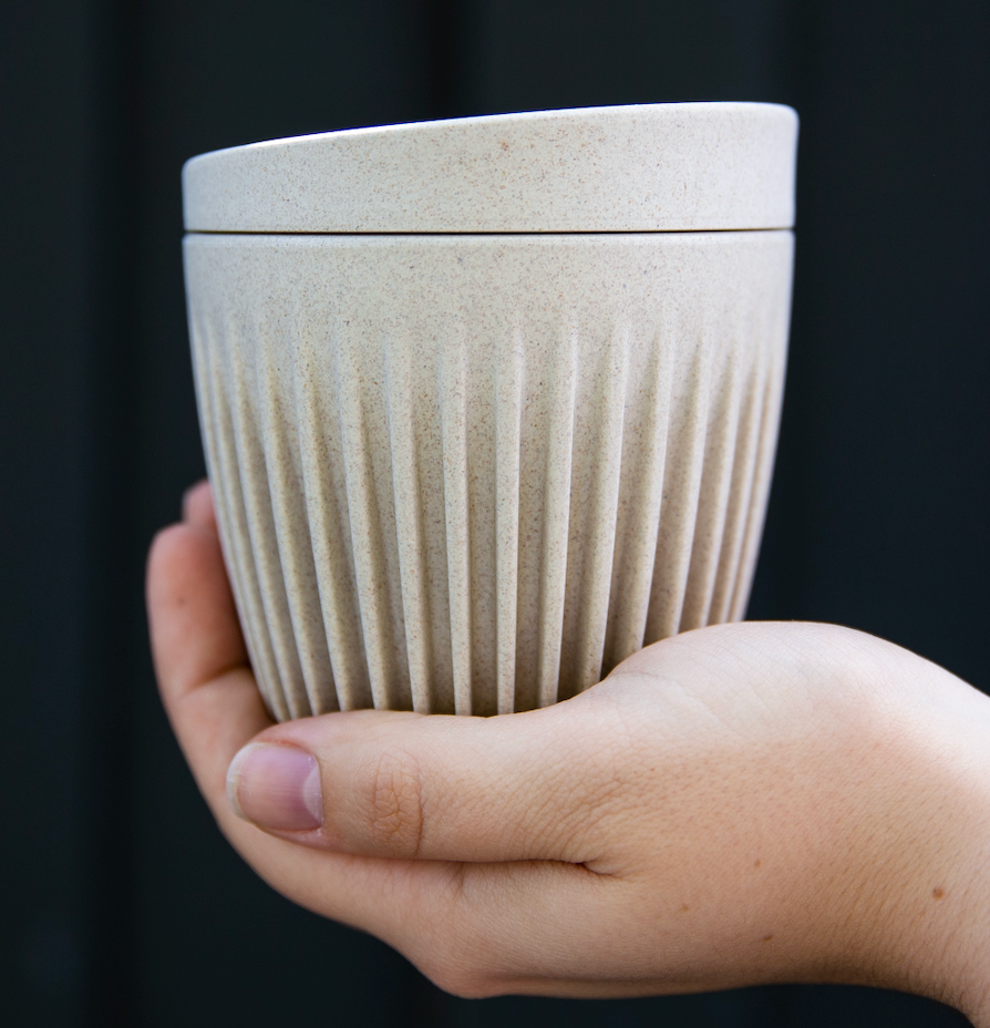 Eco-friendly reusable coffee cup with ribbed texture held in hand