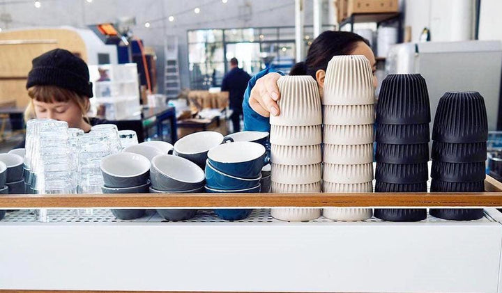 Cafe staff behind stacked HuskeeCups