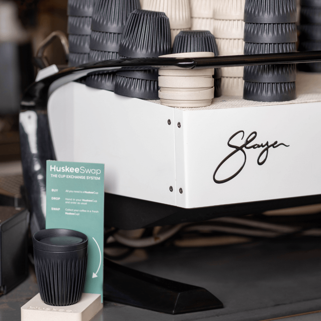 HuskeeSwap sign by cups on espresso machine