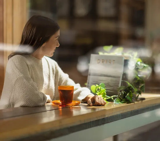 Woman with amber cup at cafe window